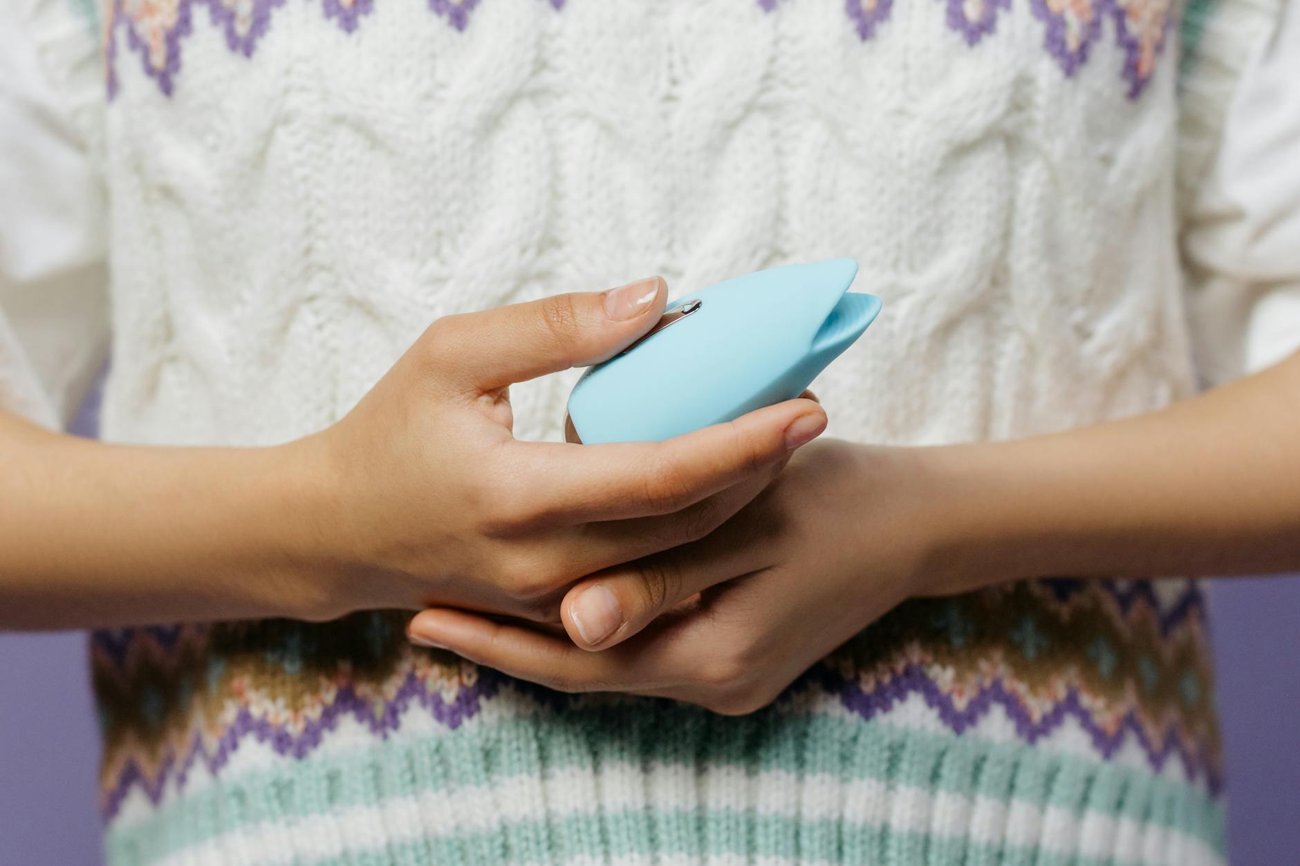 Hands holding a lemon vibrator against a knitted sweater during an extended intimate session